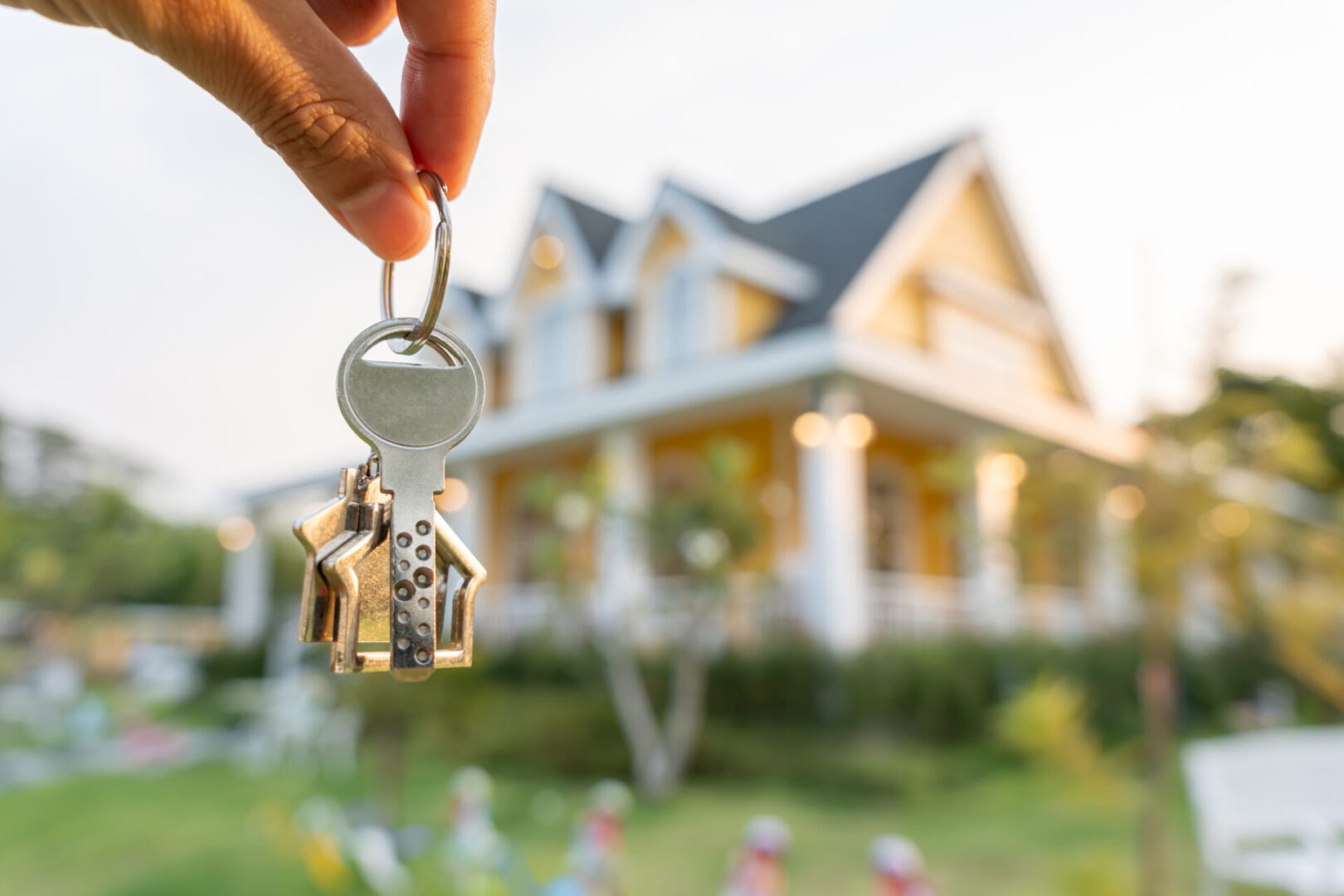 Person holding keys in front of house