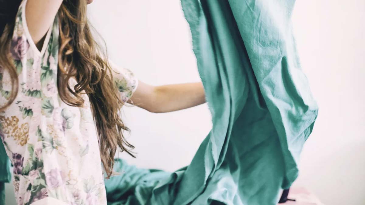 Child making bed with teal sheets