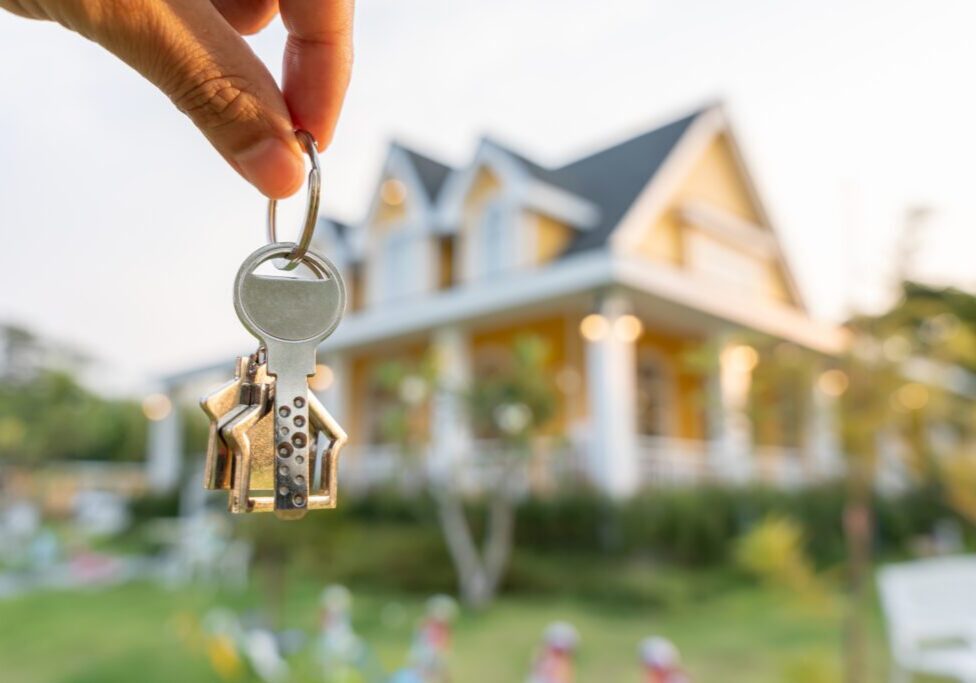 Person holding keys in front of house