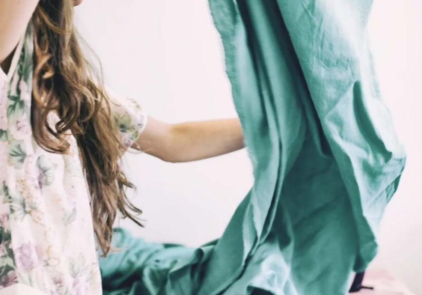Child making bed with teal sheets